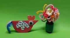 eine Vase mit gebastelten Blumen und ein Papierhuhn