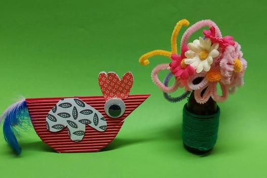 eine Vase mit gebastelten Blumen und ein Papierhuhn