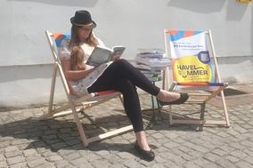 eine Frau sitzt in einem Liegestuhl und liest