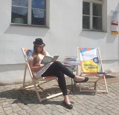 eine Frau sitzt in einem Liegestuhl und liest