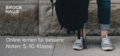 vor einer grauen Hauswand steht ein Schüler in Jeans. Es sind nur seine Beine zu sehen