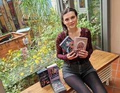 eine junge Frau sitzt auf einer Bank in der Bibliothek und hält zwei Bücher in den Händen